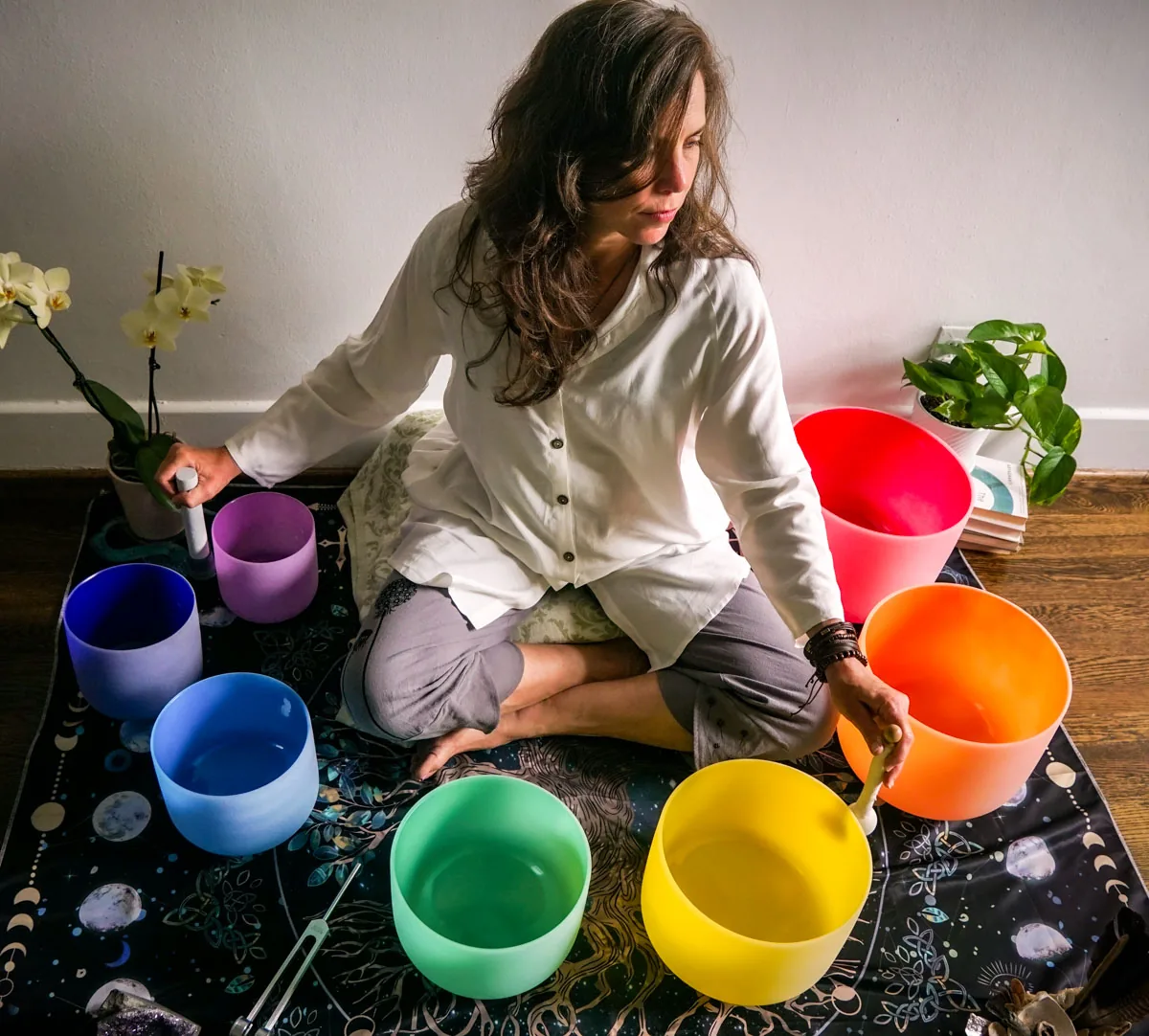 A practitioner playing colorful crystal singing bowls during a sound healing event