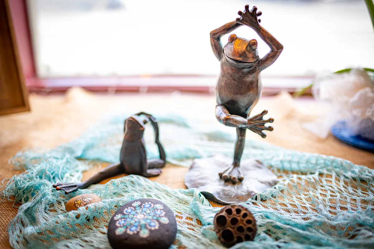 A bronze yoga frog and painted mandala stones on the studio windowsill